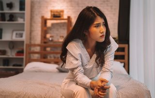 woman sitting on edge of bed wondering about the types of mental illness