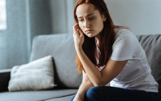 a woman sitting on her couch struggling with heroin withdrawal