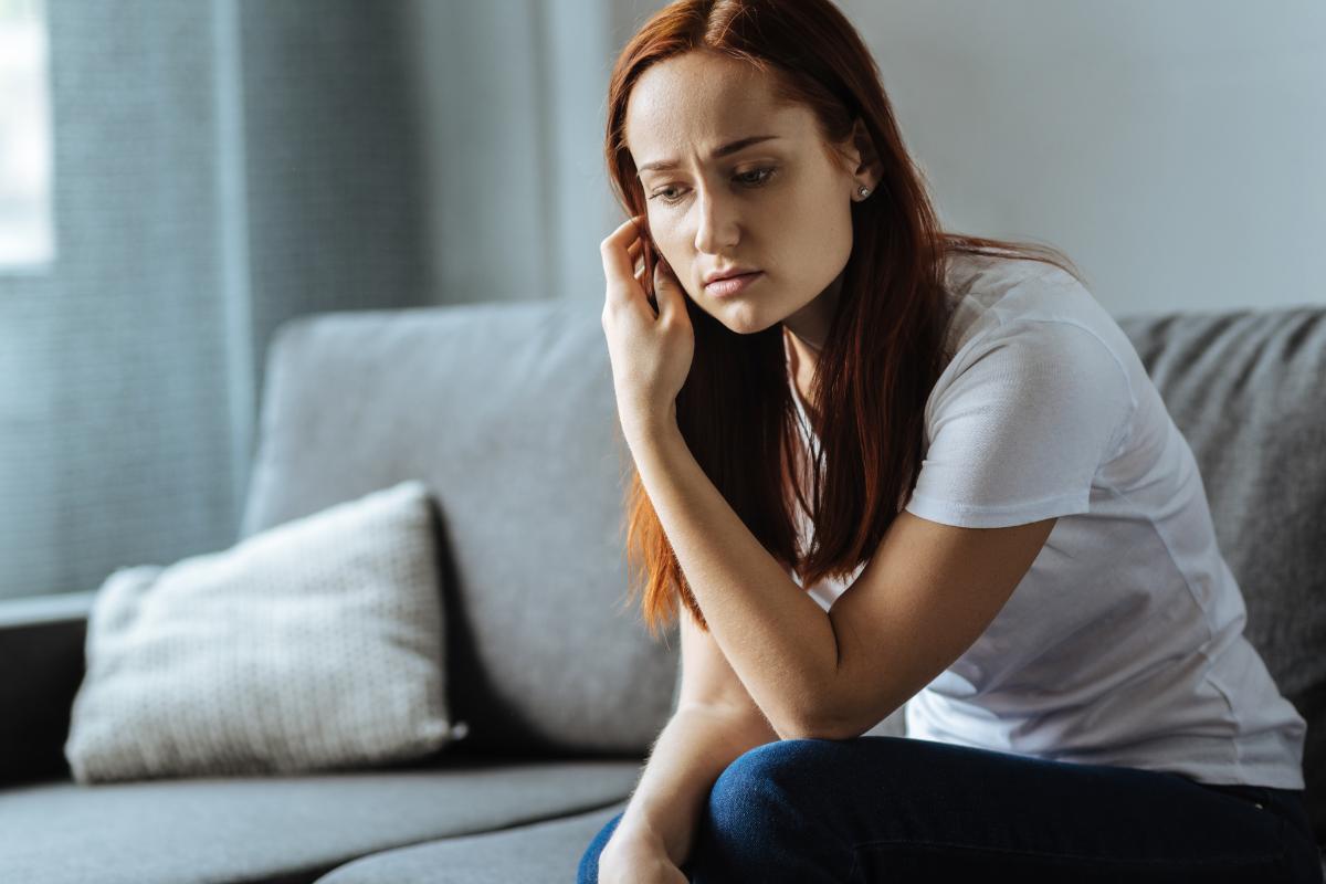 a woman sitting on her couch struggling with heroin withdrawal