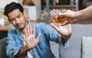 man refusing a glass of whiskey because he quit drinking - get help to quit drinking concept image