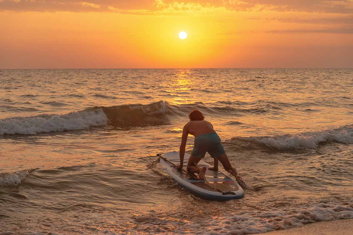man paddle boarding in the ocean practicing sober activities