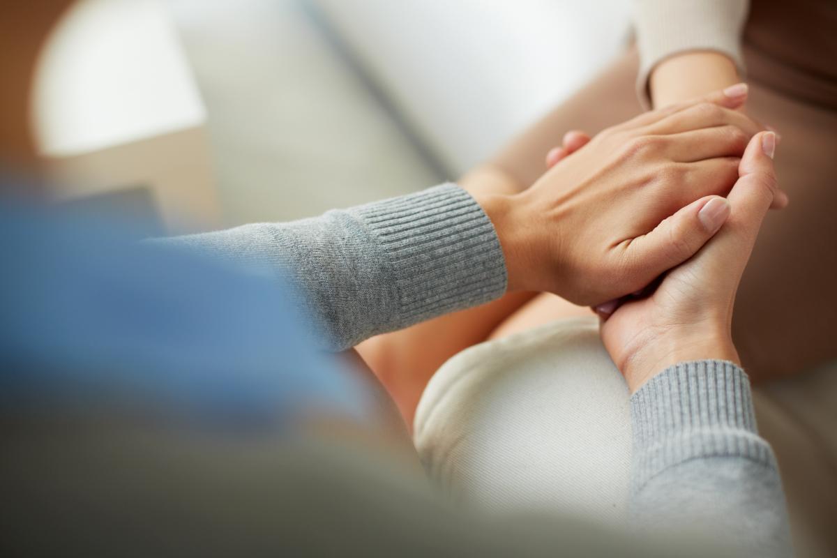 Two people holding hands through addiction counseling