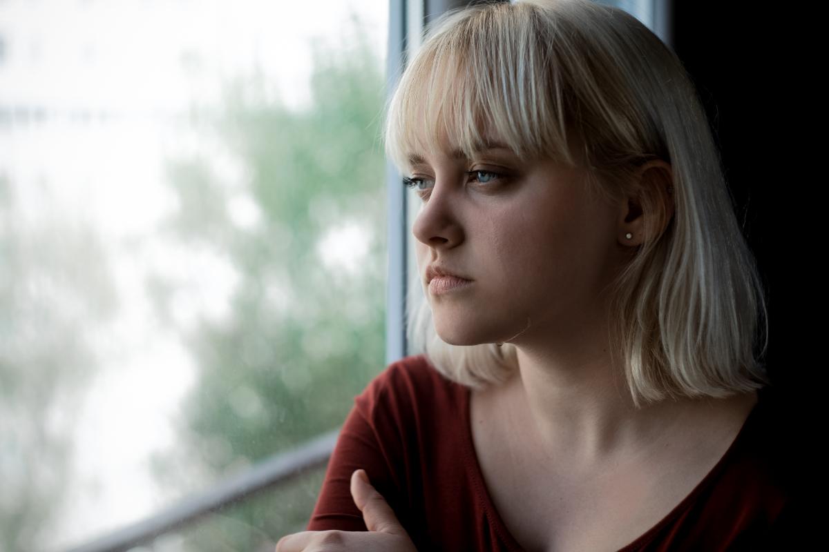 woman looking out window dealing with signs of opioid addiction