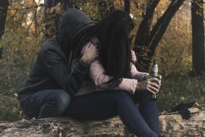 Woman drinking bear in park with boyfriend - relationships and addiction