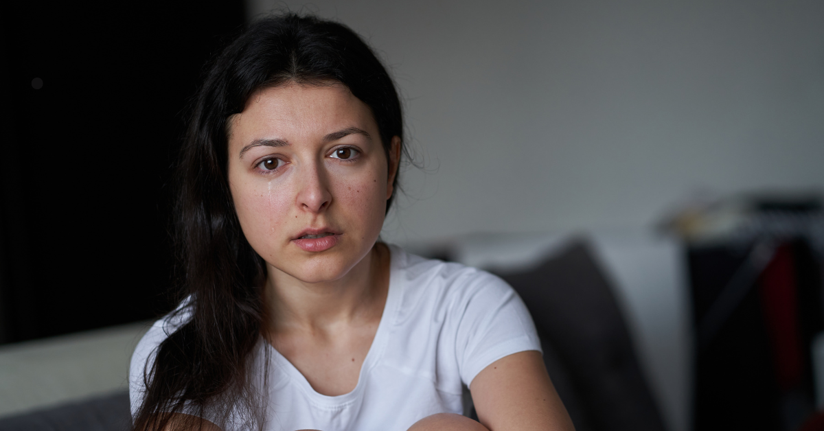 A dark haired woman with a tear running down her face.