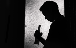 Sad man looking into beer bottle