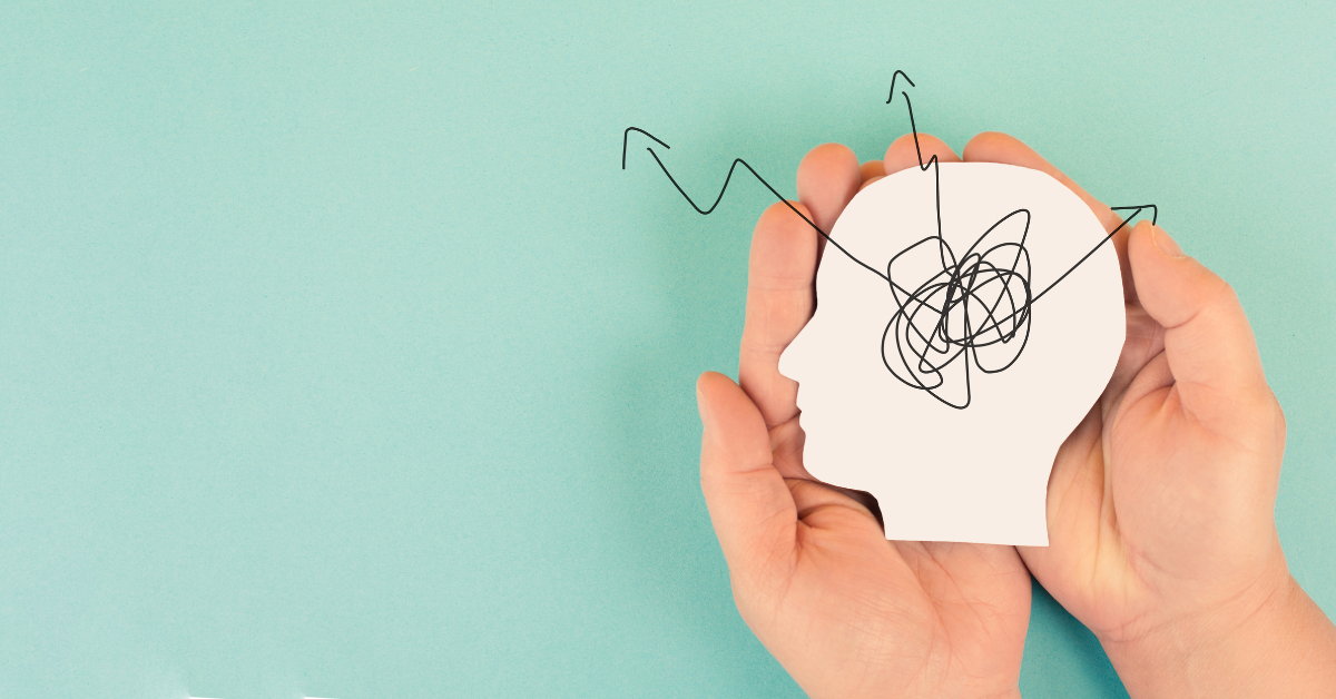 Hands hold a paper silhouette of a head that had squiggled lines in the center that point out in arrows.