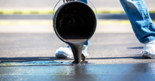 Blac tar being poured on pavement.