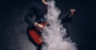 Faceless man with a guitar surrounded by smoke.