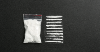 Lines of cocaine next to a filled baggy.