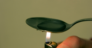 A spoon is heated with a lighter.
